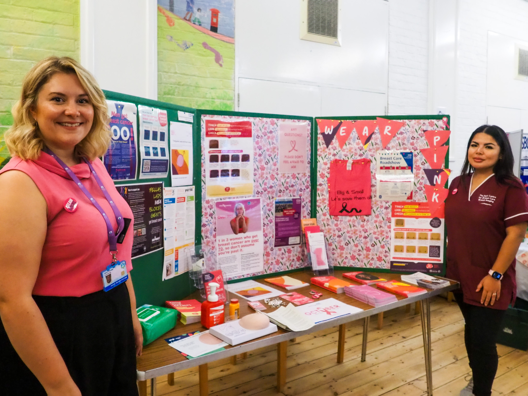 Two women standing in front of a cancer awareness community display.