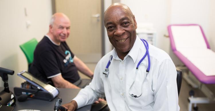 Doctor smiling with patient in GP office.