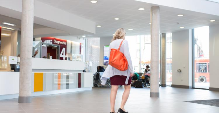 Woman walking through a hospital lobby to the entrance doors.