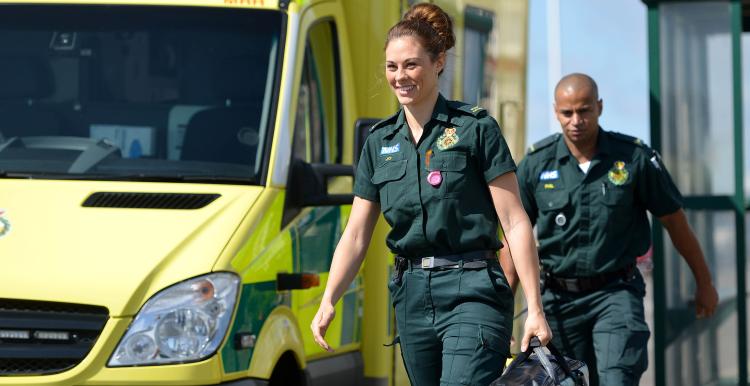 Two paramedics walking alongside a South East Coast Ambulance.