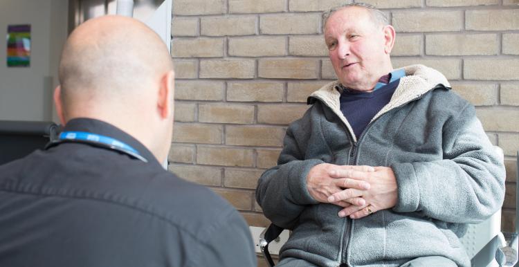 An older man being spoken to by another man.