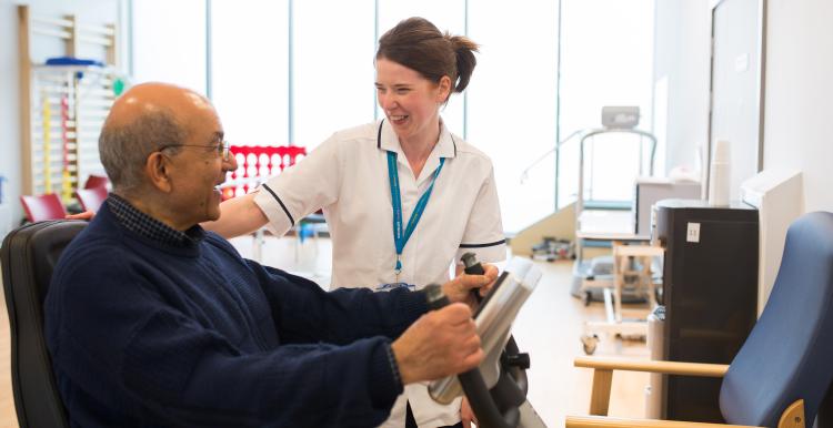 An older man and healthcare professional laughing together.