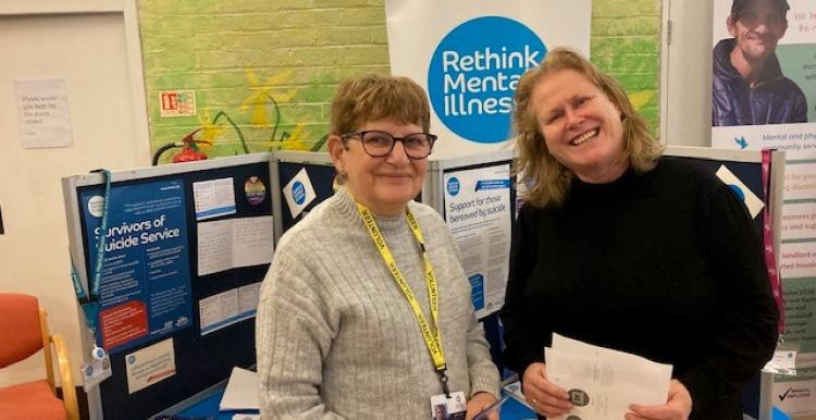 Two women standing in front of a 'rethink mental illness' community display.