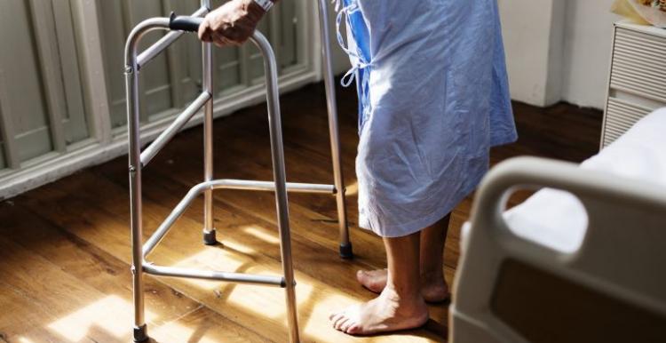 photograph, side view looking to floor, close up of patient holding zimmer frame