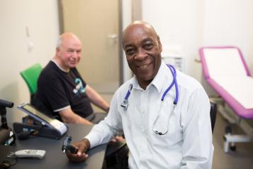 Doctor smiling with patient in GP office.