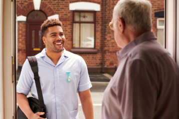 Carer smiling at man in doorway.