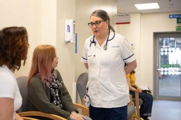 A clinician talking to two people in a waiting area