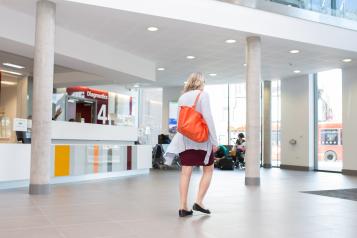 Woman walking through a hospital lobby to the entrance doors.