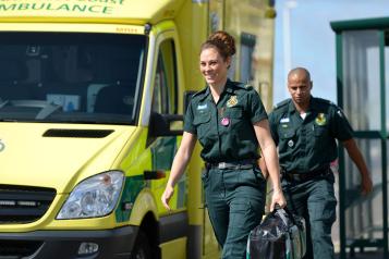 Two paramedics walking alongside a South East Coast Ambulance.