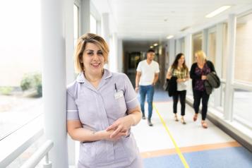 Medical professional standing in corridor with three people walking behind them.