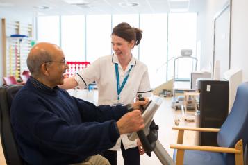 An older man and healthcare professional laughing together.