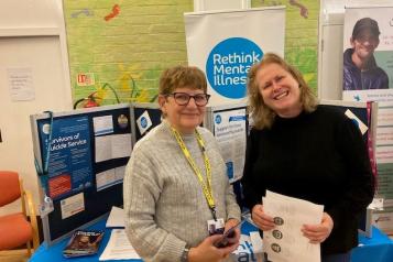 Two women standing in front of a 'rethink mental illness' community display.