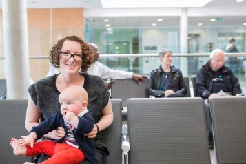 Woman with a baby on her lap in a waiting room.