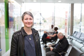 A woman standing in a waiting room smiling at the camera.