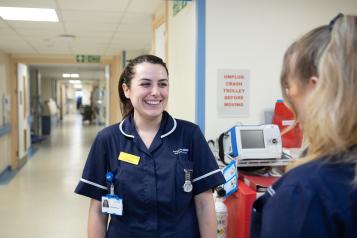 Two medical professionals talking in a corridor in a hospital setting.