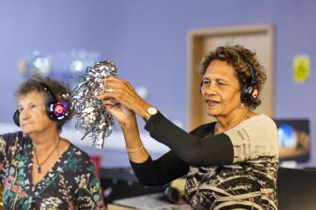 Two older women taking part in a creative dance exercise indoors.