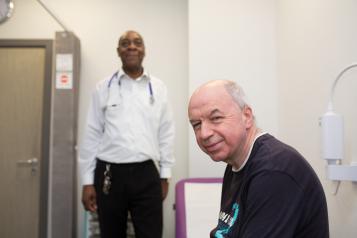 GP Surgery, Man in focus, in foreground to right, Doctor blurred, in background to left