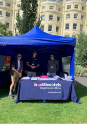 Healthwatch team standing under gazebo at festival.