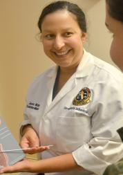 Doctor holding board, in front of patient